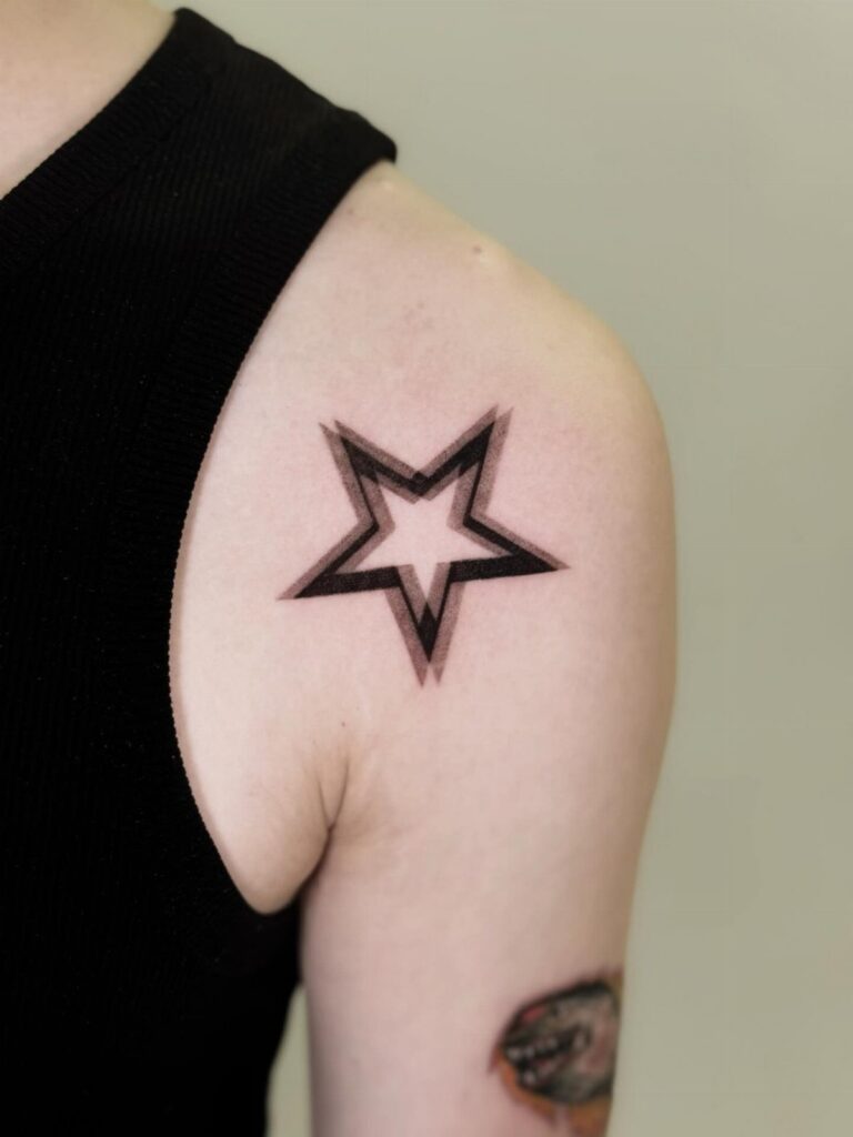 Five-pointed star tattoo with bold black outlines on a person's upper arm.