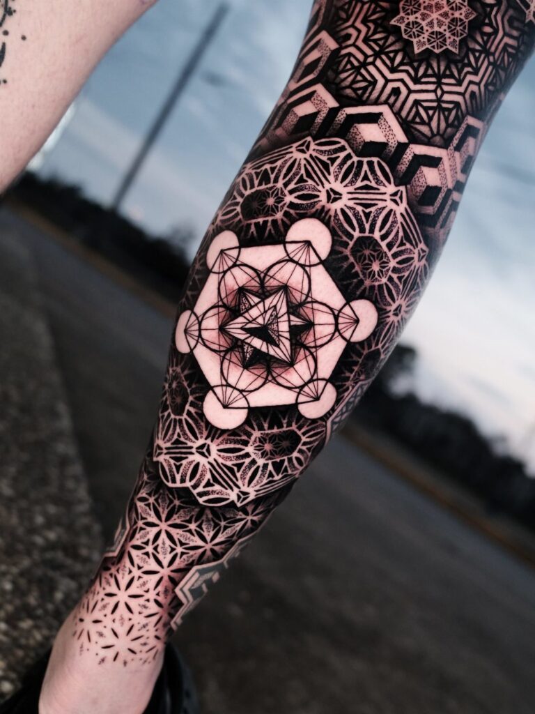 Detailed black ink geometric and sacred geometry tattoo on a person's forearm.
