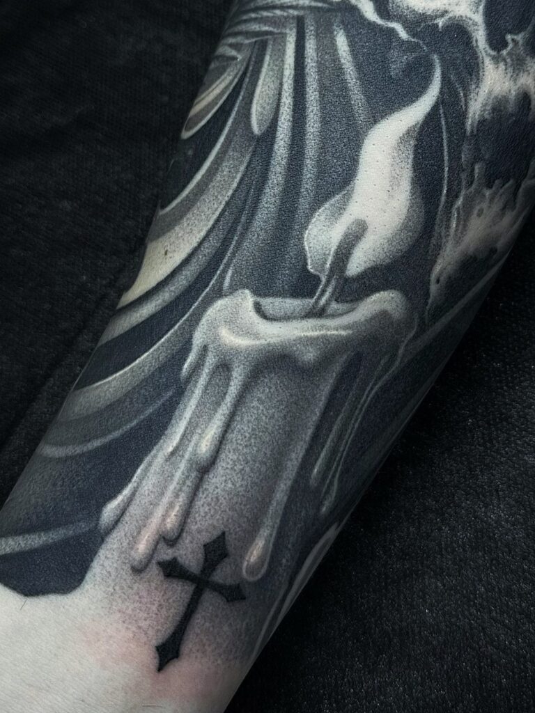 Melting candle tattoo with a flame and cross in black and grey ink.