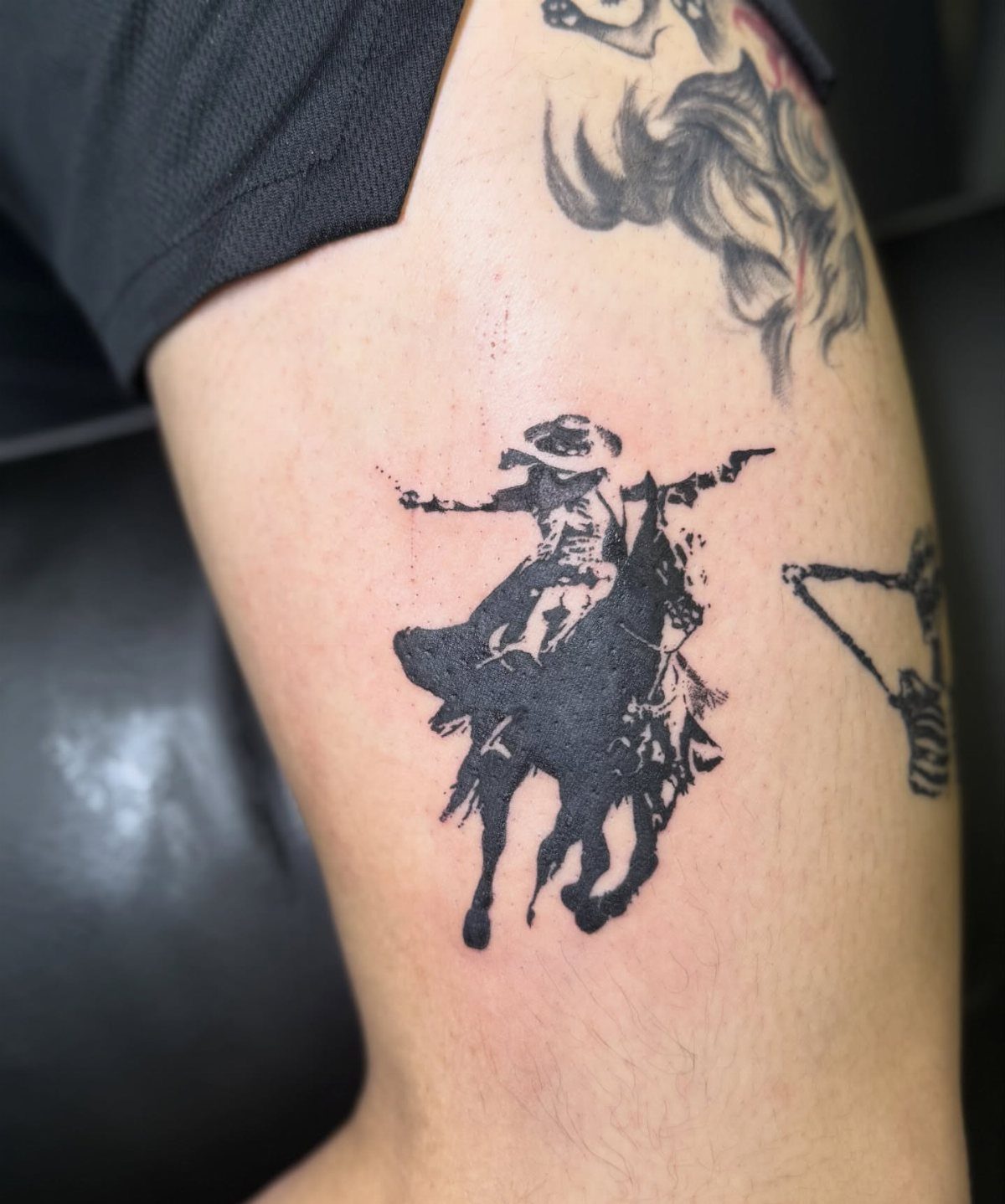 Cowboy silhouette tattoo on a leg showing a rider on a bucking horse