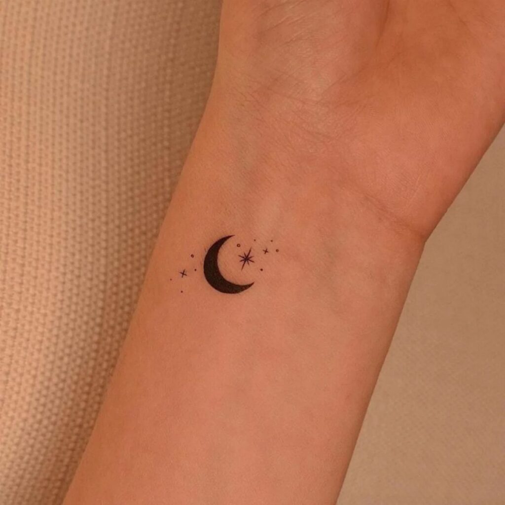 Crescent moon and star tattoo on a person's inner wrist
