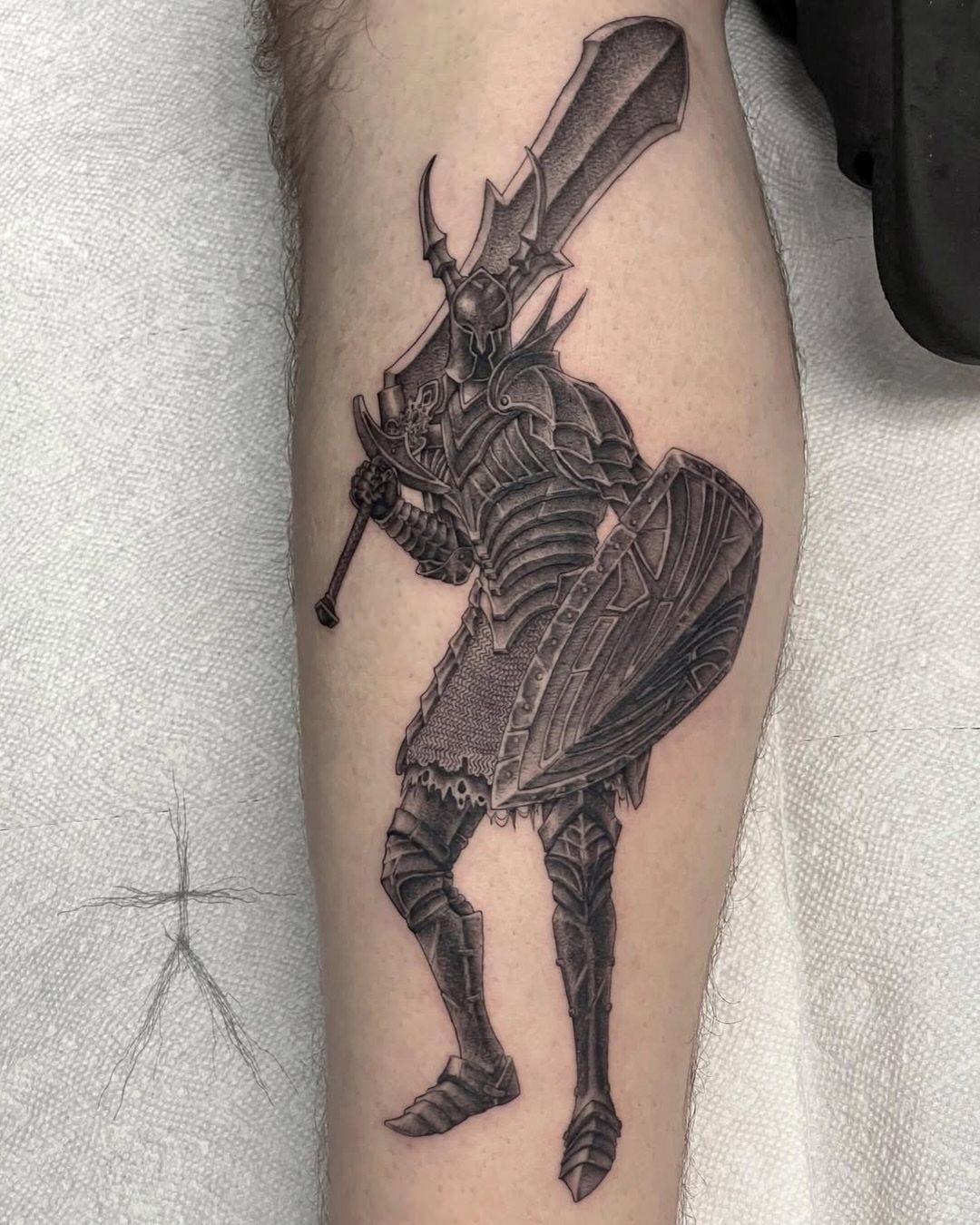 Armored knight tattoo with sword and shield on a person's leg.