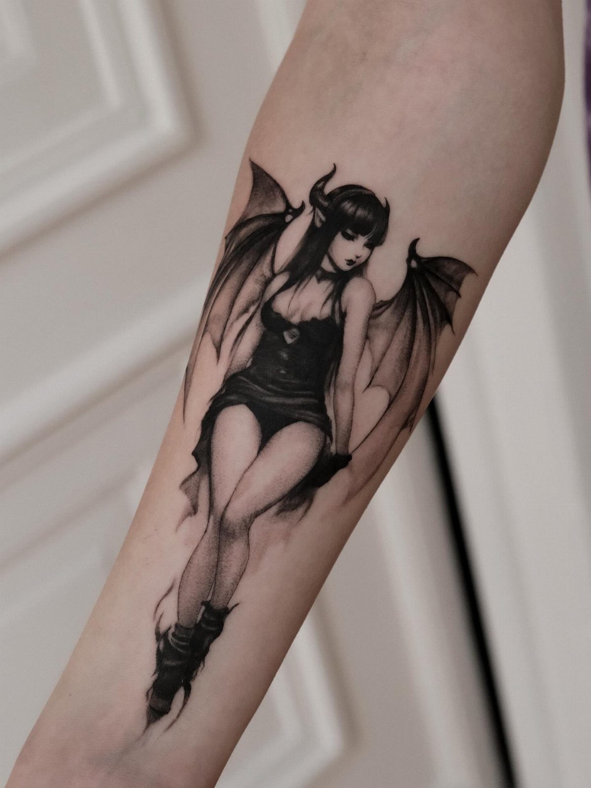 Gothic fairy tattoo on a forearm featuring a winged woman with horns.