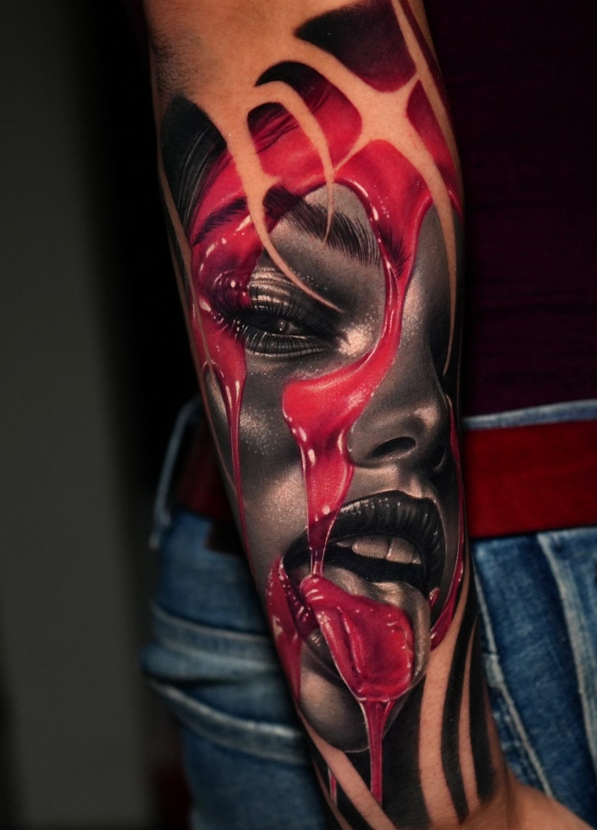 High contrast tattoo of a woman's face with dripping red liquid on a forearm.