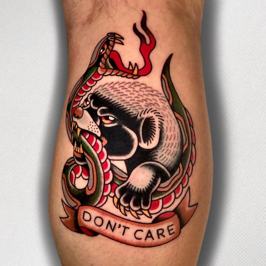 Honey badger tattoo fighting a snake with a Don't Care banner on a leg