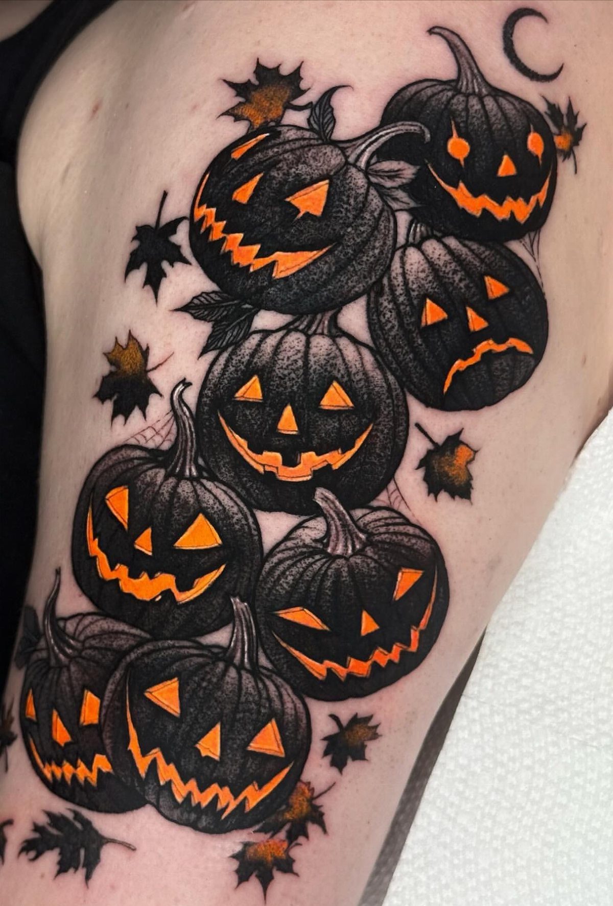 Jack-o'-lantern tattoo with multiple black pumpkins and orange carved faces on skin