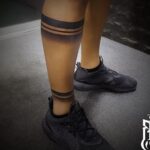 Black band tattoos wrapped around the upper calf and ankle of a person's leg.