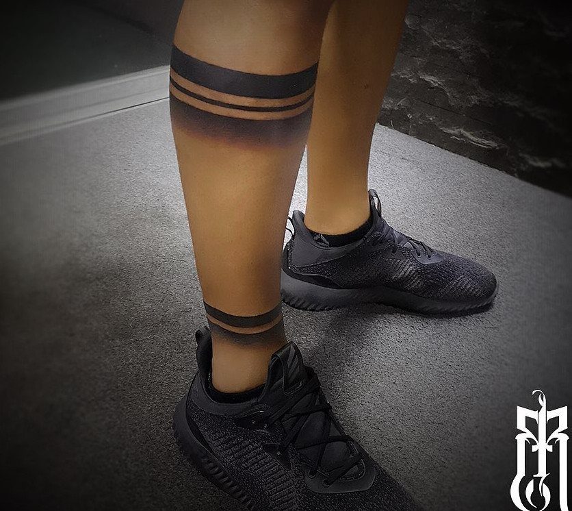 Black band tattoos wrapped around the upper calf and ankle of a person's leg.