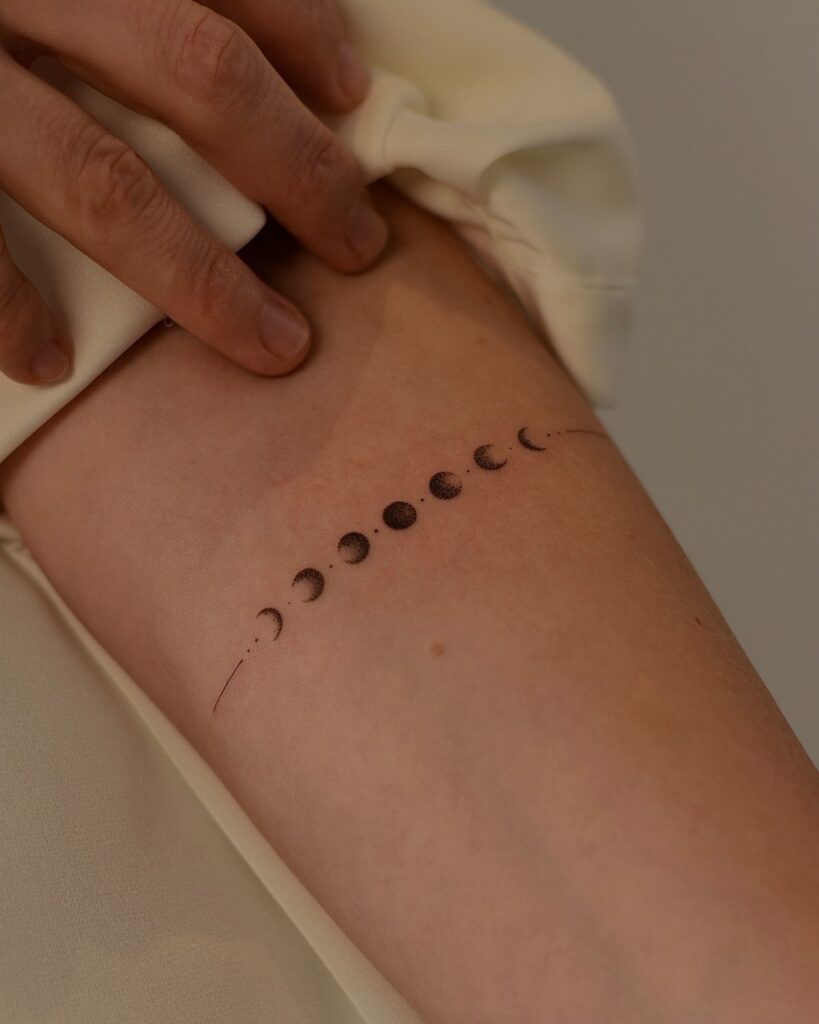 Moon cycle tattoo on a person's arm showing the different phases of the moon.