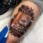 Pin up girl tattoo inside a polaroid frame with red roses on a thigh