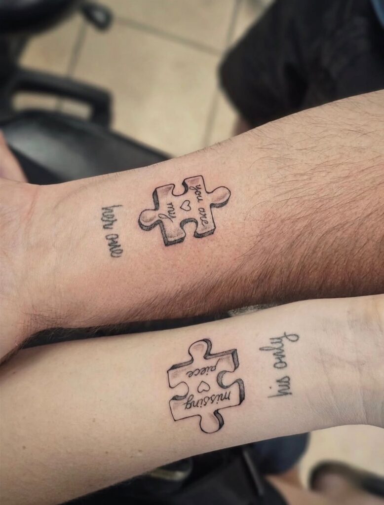 Matching puzzle piece tattoos on two forearms with accompanying cursive text.