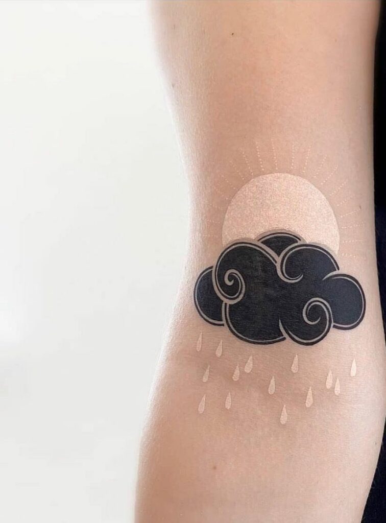 Rain cloud tattoo with white raindrops and a pale sun on an arm.
