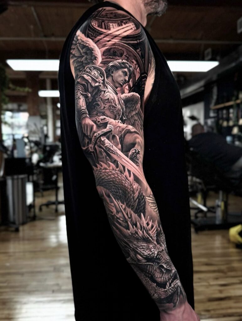 Realistic black and grey tattoo sleeve of an armored angel fighting a dragon.