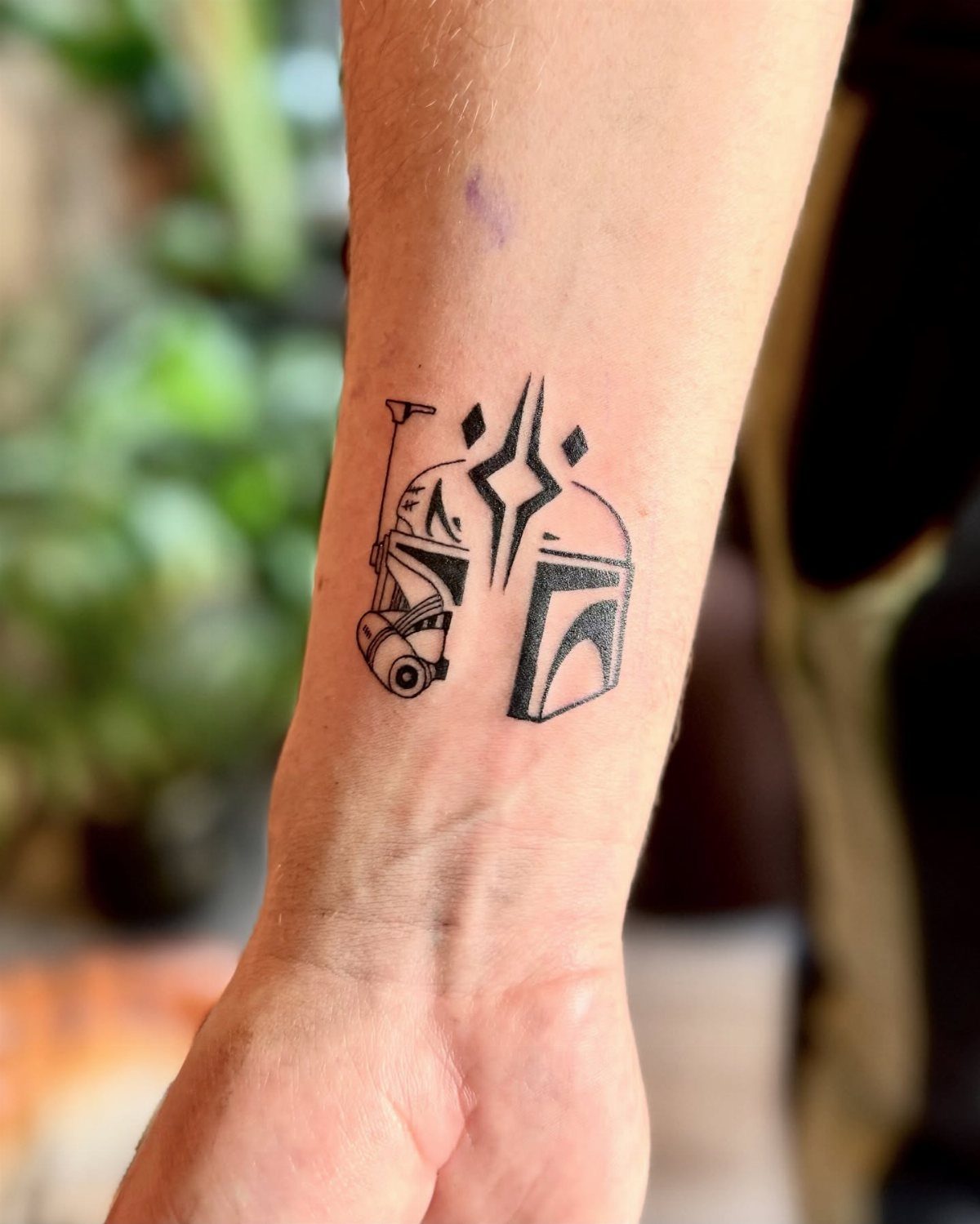 Black ink Star Wars helmet tattoos on a person's inner wrist.