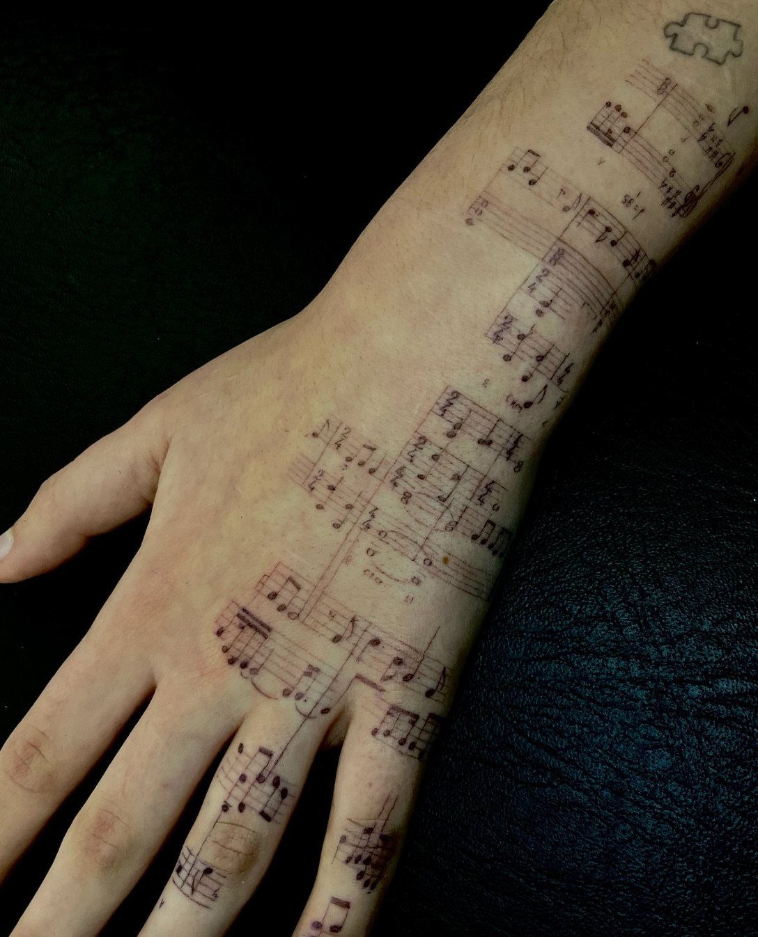 Musical staff and notes tattooed across a person's hand and wrist.