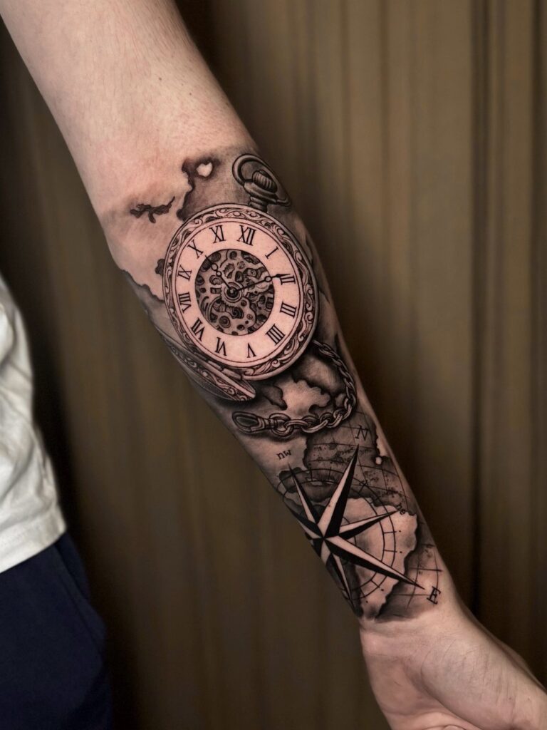 Pocket watch and compass tattoo on a person's forearm in black and grey ink.
